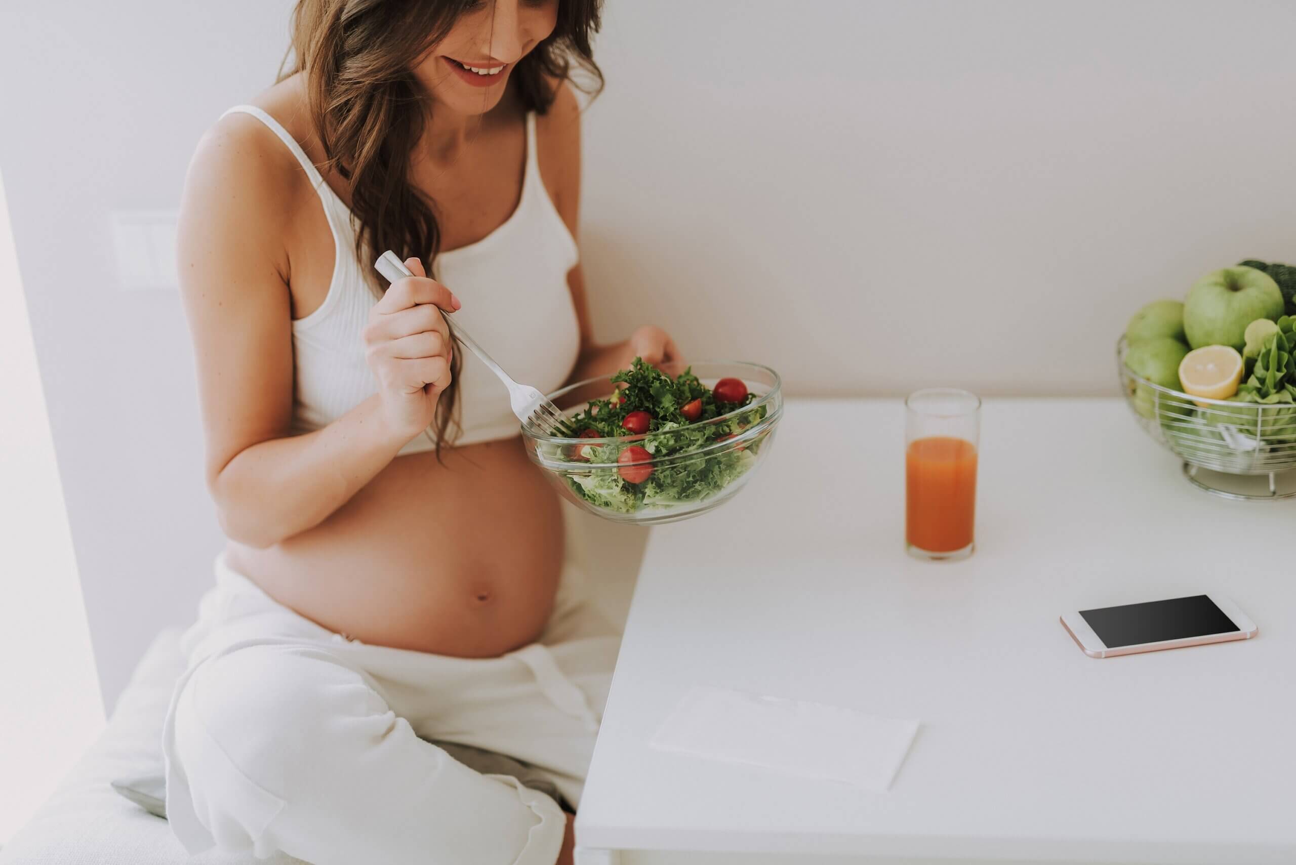 Une femme enceinte qui mange une salade.