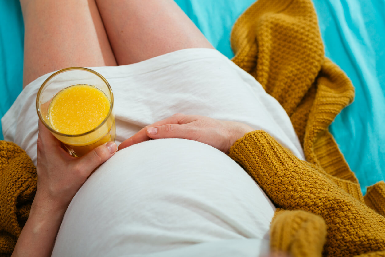 Une femme enceinte qui boit du jus d'orange;