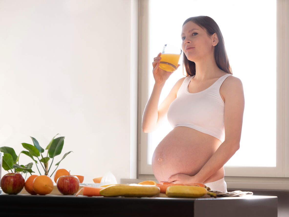 A pregnancy woman drinking orange juice.