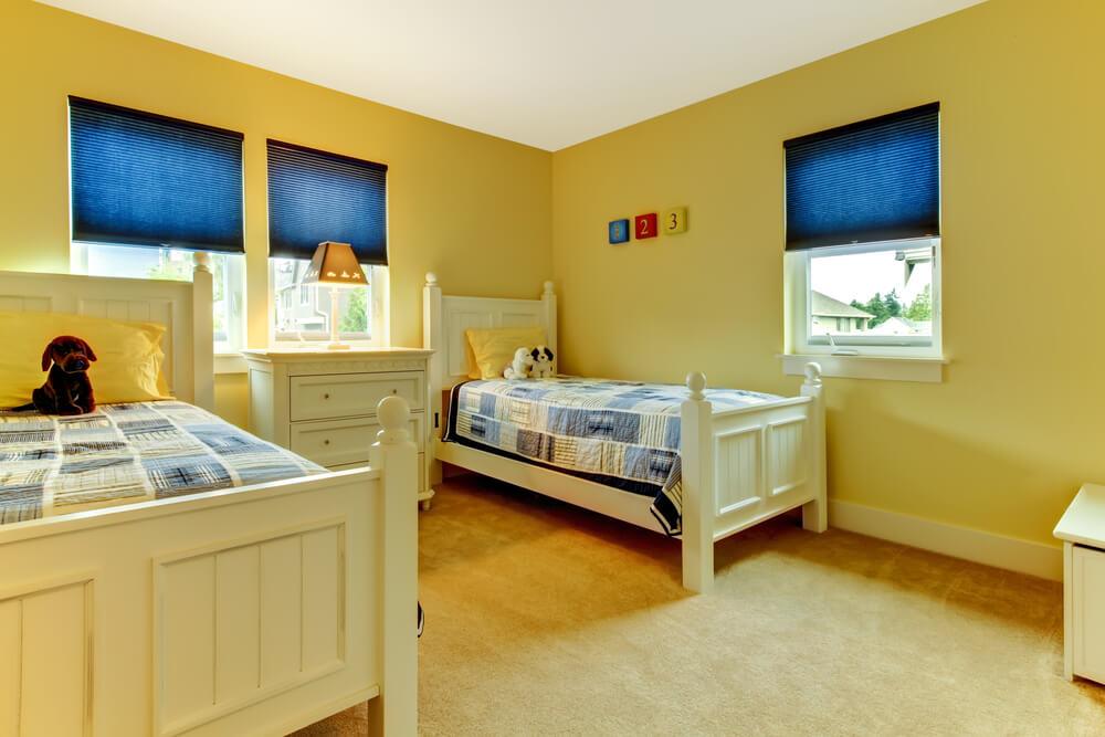 A child's bedroom with blue blinds in the windows.
