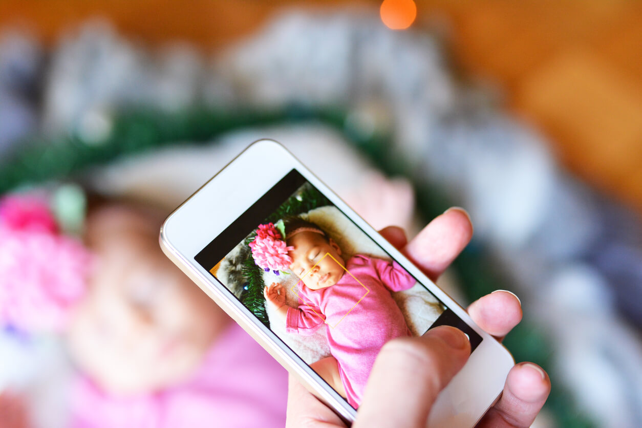 A mother taking a picture of her sleeping baby.