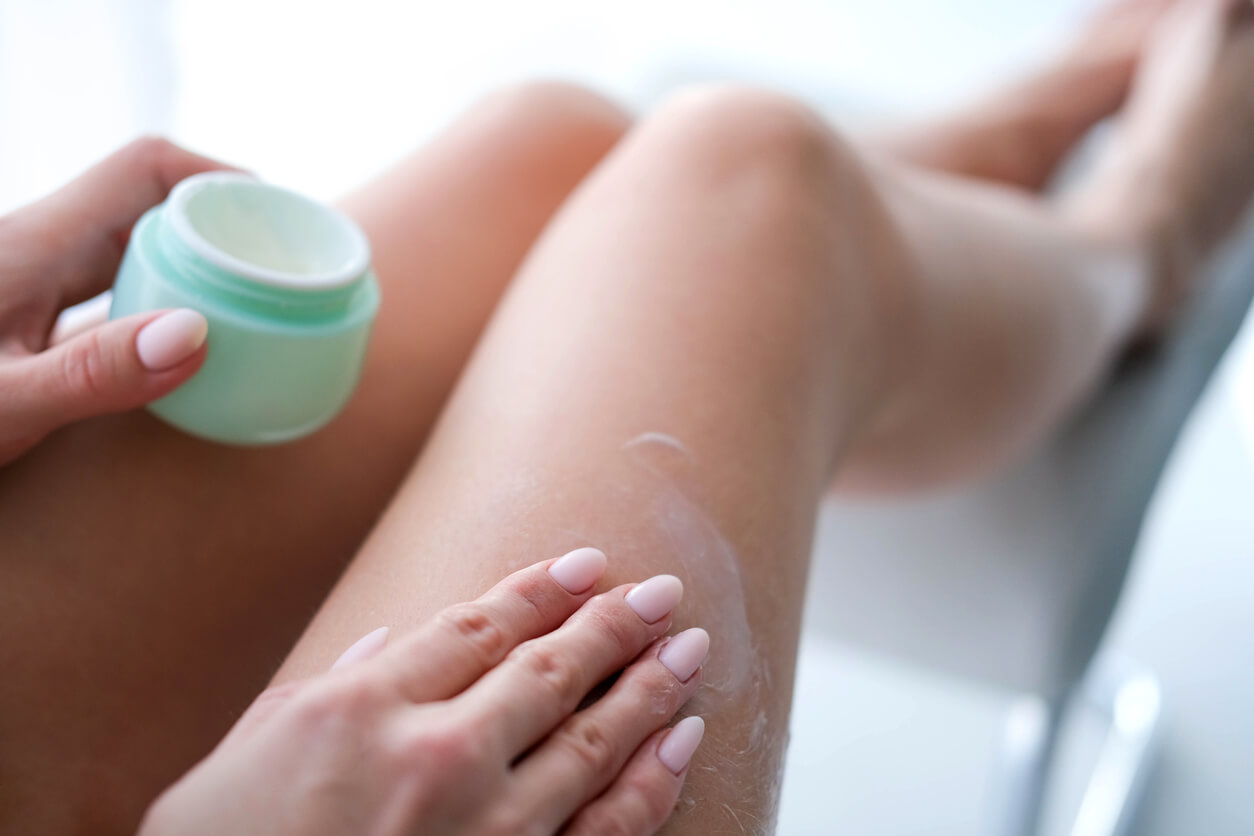 A woman putting lotion on her legs.