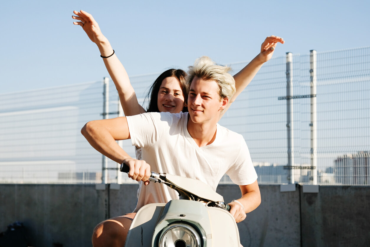 A teenage boy and girl riding on a motorcycle.