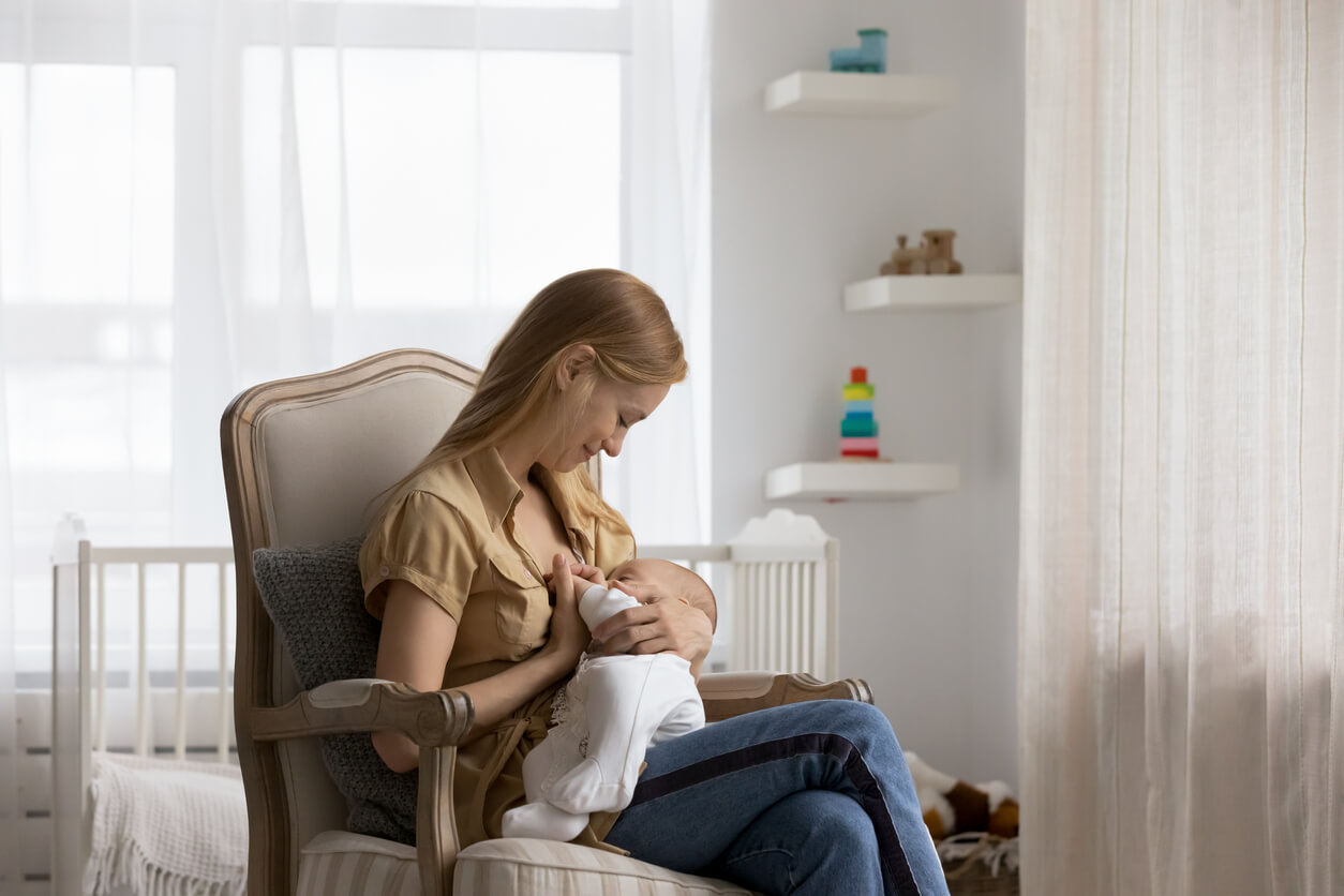 A woman breastfeeding her baby in a rocking chair.