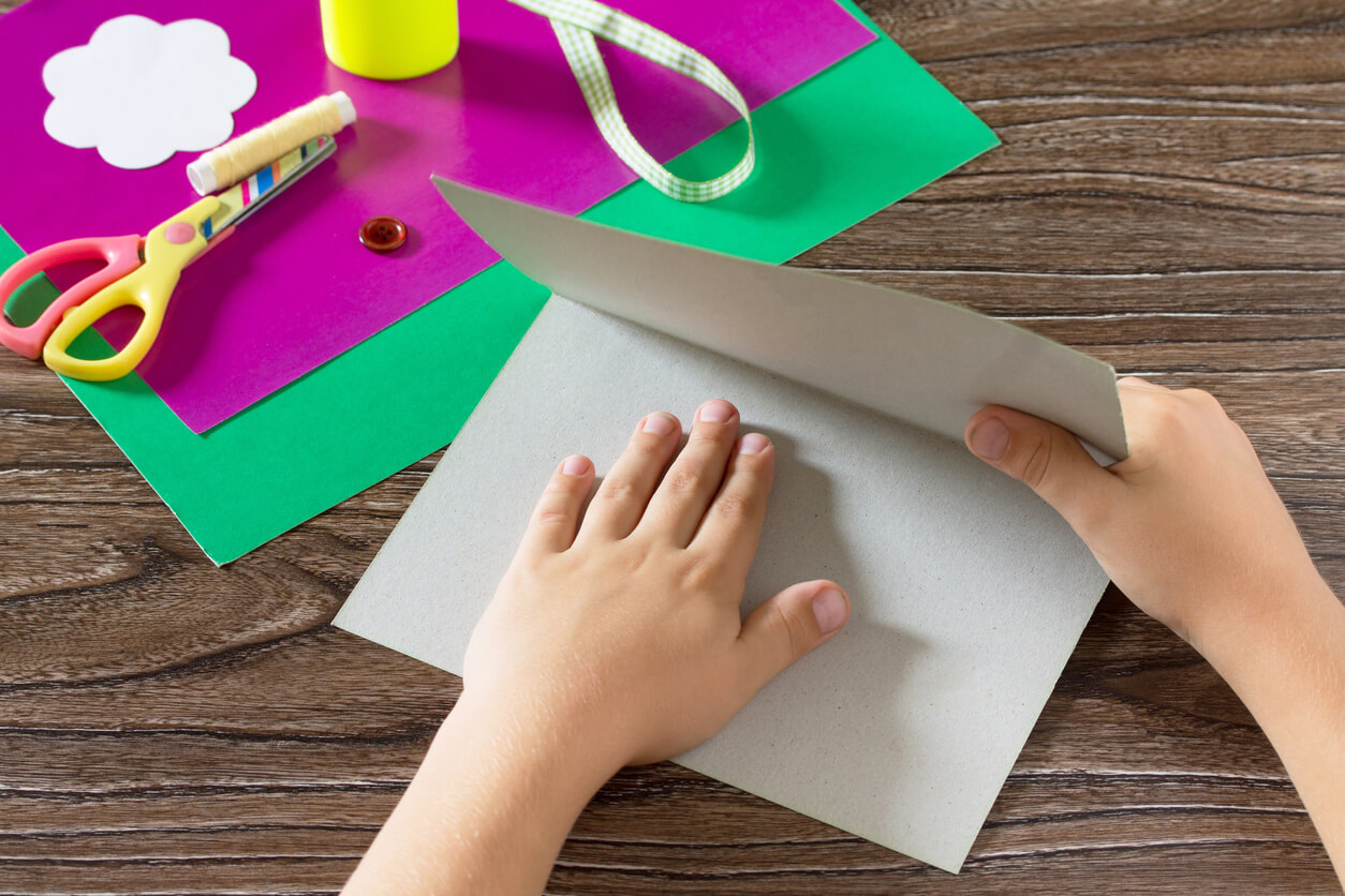Ett barn viker ett papper på mitten.