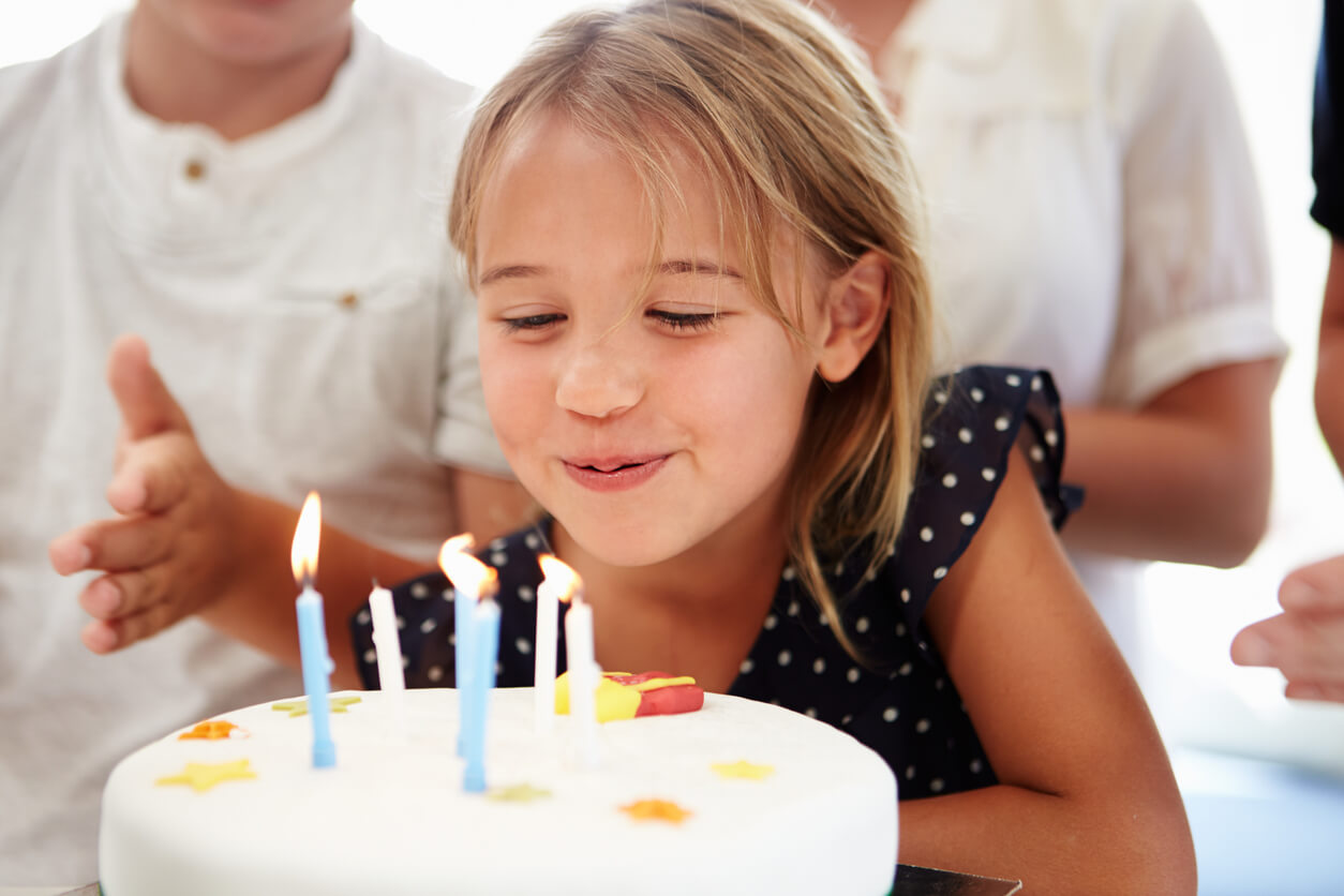 A little girl blowing out the candles on her birthday cake.