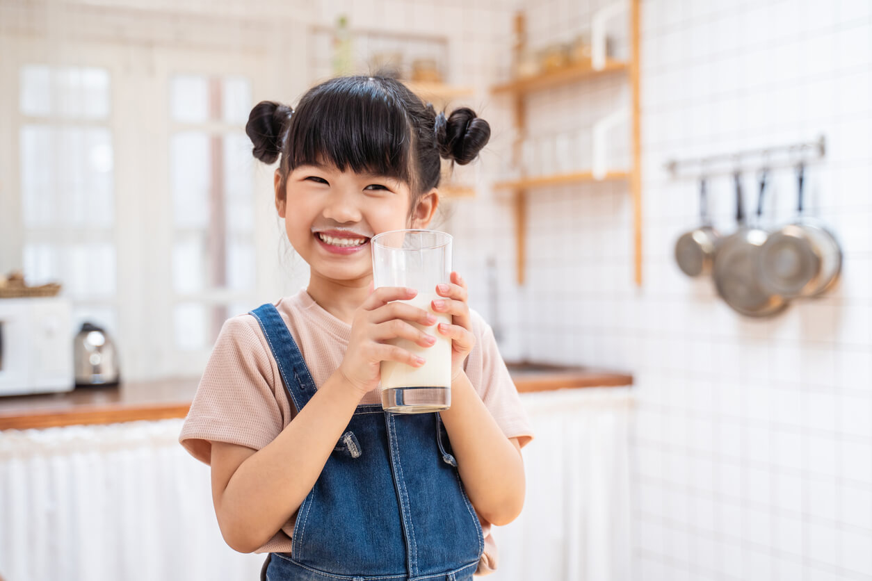 En ung flicka som dricker mjölk och ler.