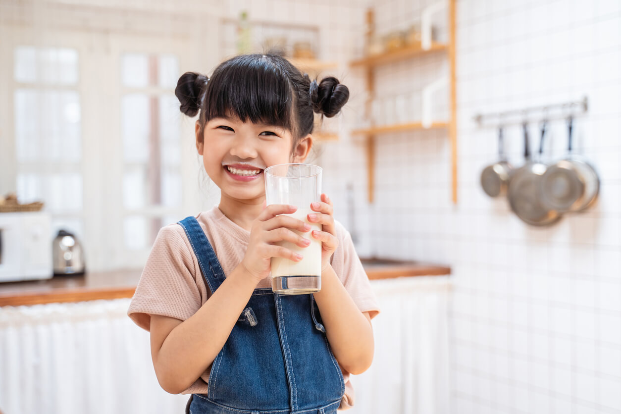 A young girl drinking milk and smiling.