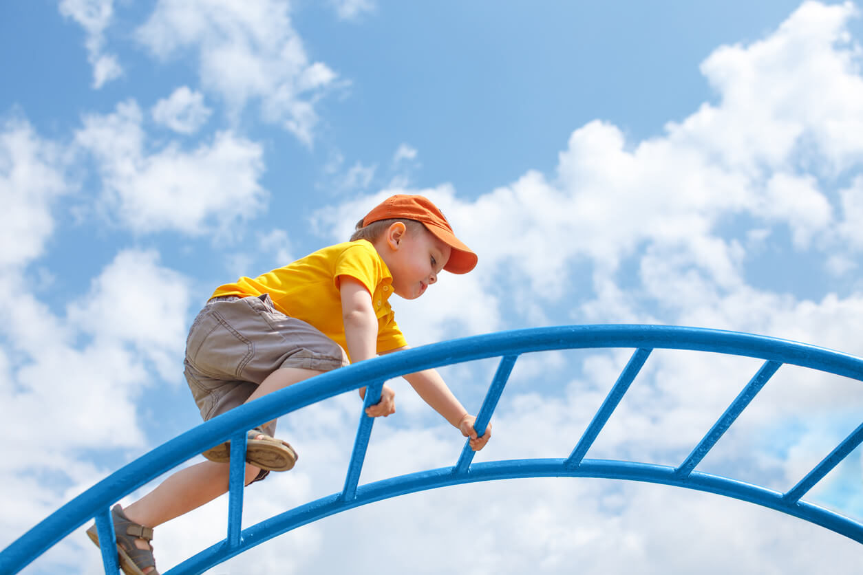 Et barn som klatrer på en lekeplass.