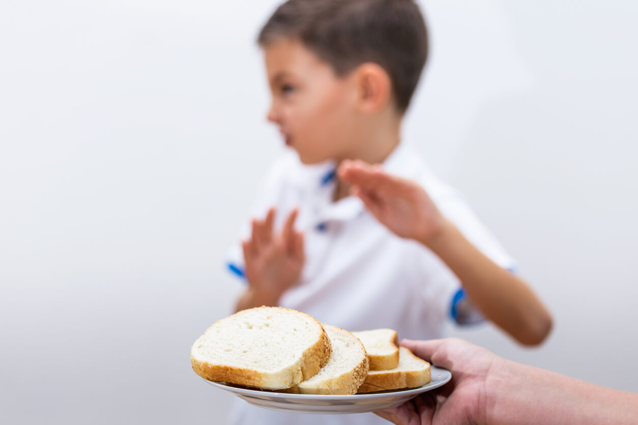 A child refusing a plate of bread.