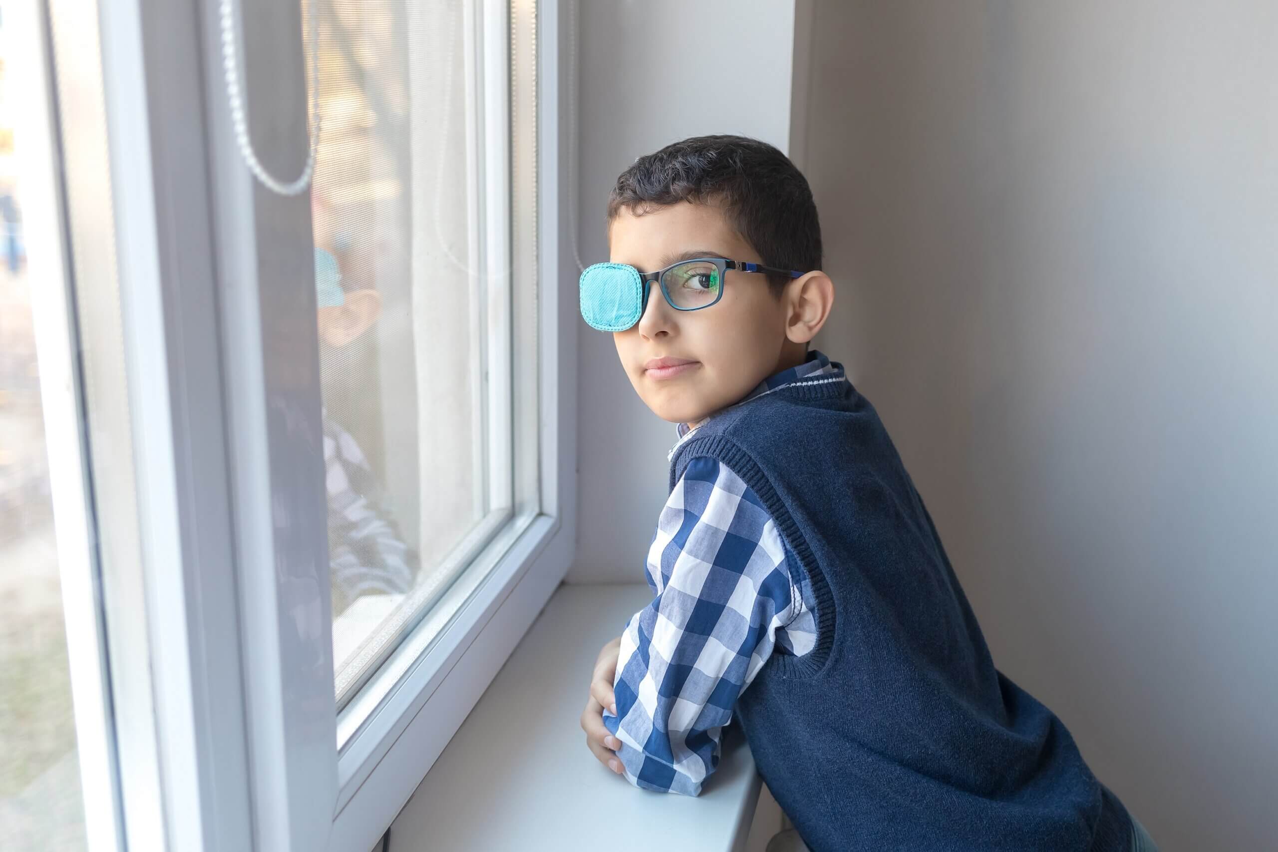 A boy wearing glasses with a patch over one side.
