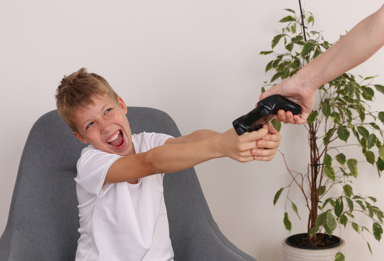 A mother and child fighting over a video game controller.