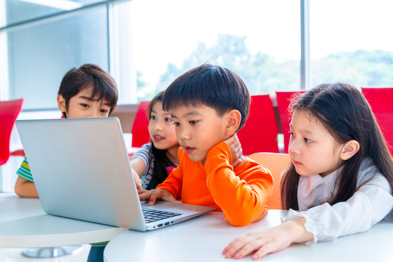 Elementary students learning on a laptop computer.