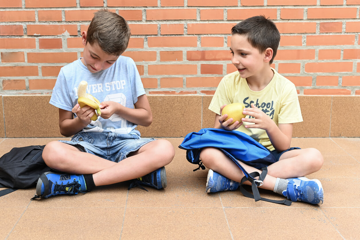 Two children eating fruit as a snack at school.