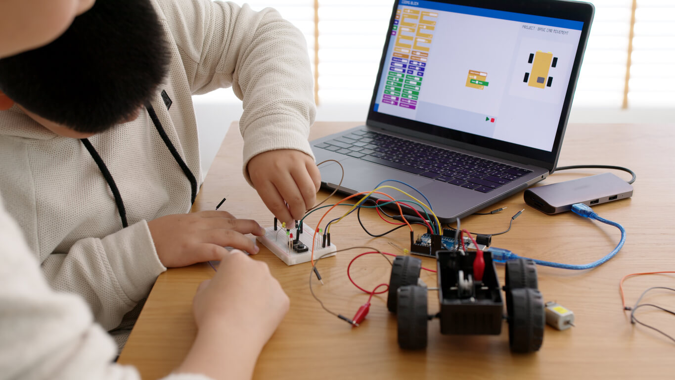 Children using a computer to control an electric toy car.