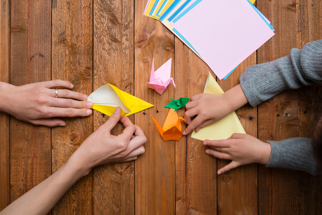 A mother and her child making origami birds.