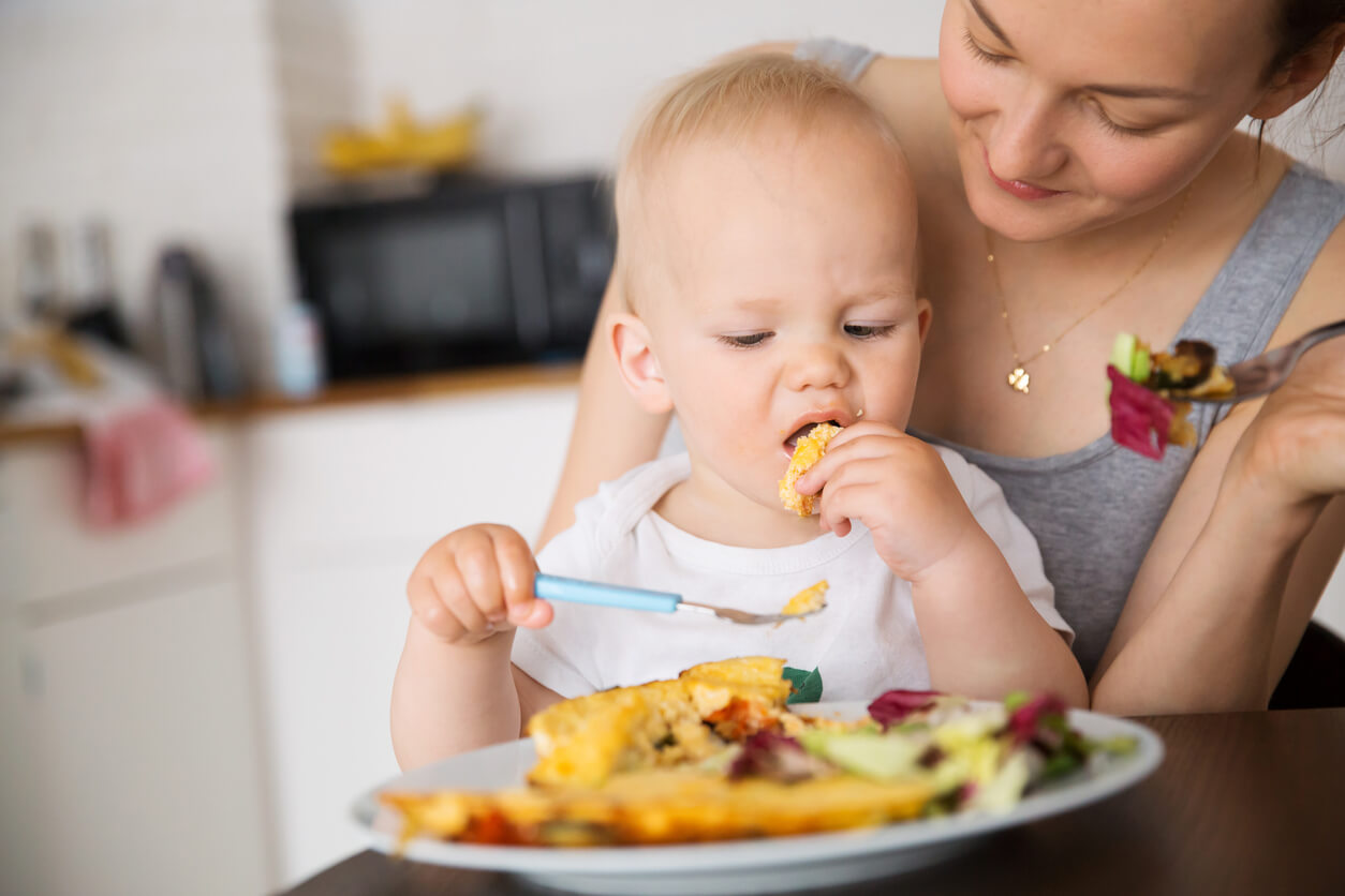 A toddler eating an omelette with his fingers.