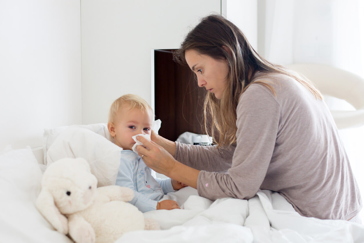 En mamma som torkar sin bebis näsa.