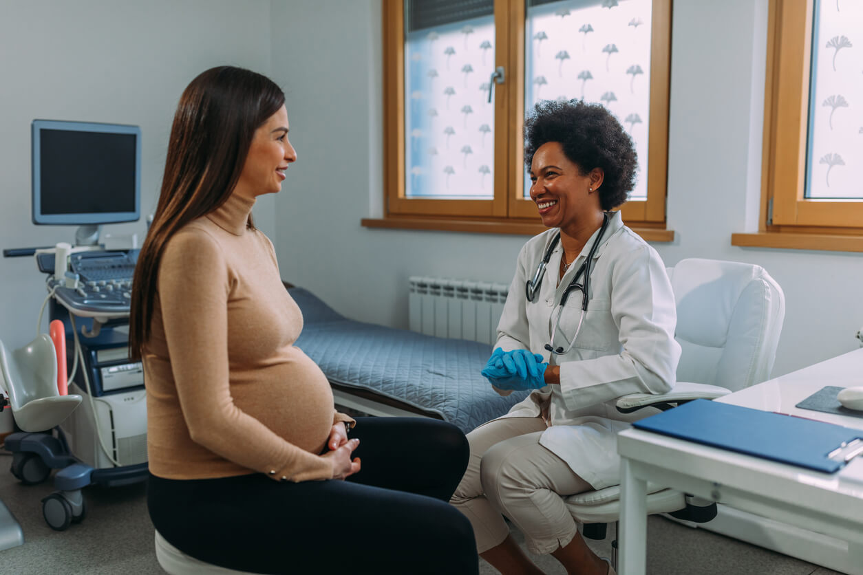 A pregnant woman talking with her OB/GYN.