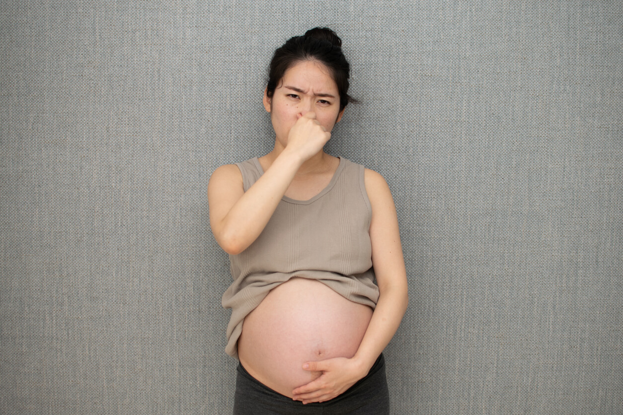 A pregnant woman plugging her nose.
