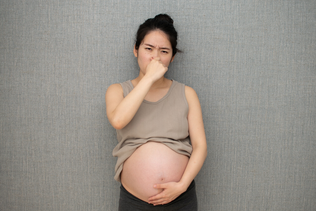 En gravid kvinne tetter nesen.
