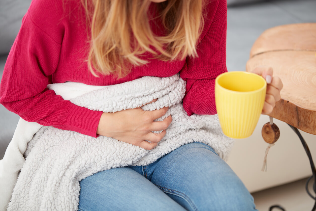 A woman with stomach pain drinking tea.