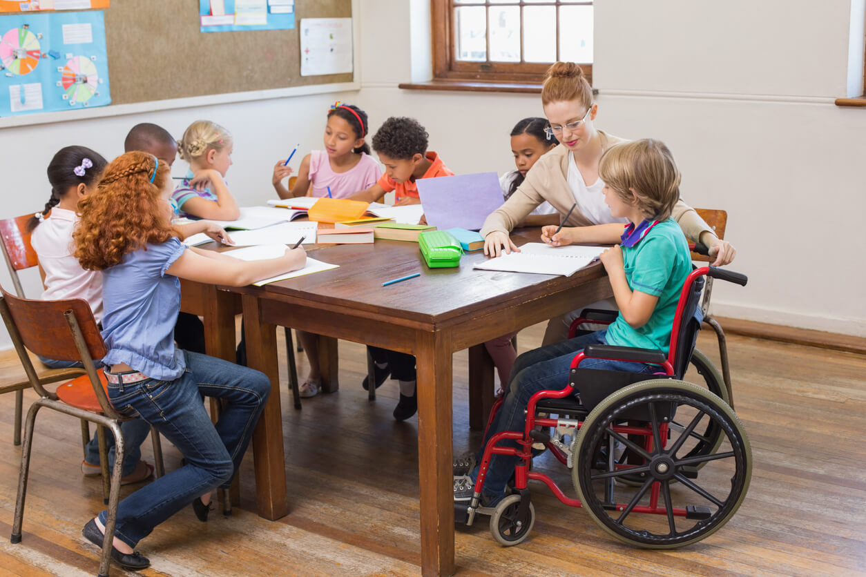 Elementary students, one of whom uses a wheelchair, sitting at a table.