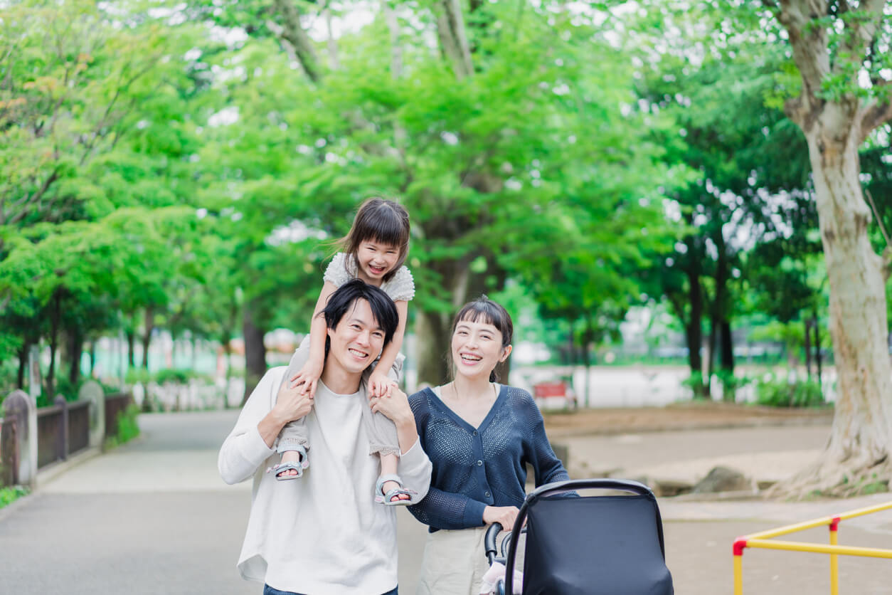 Japanilainen perhe hymyilee kävelyllä puistossa.
