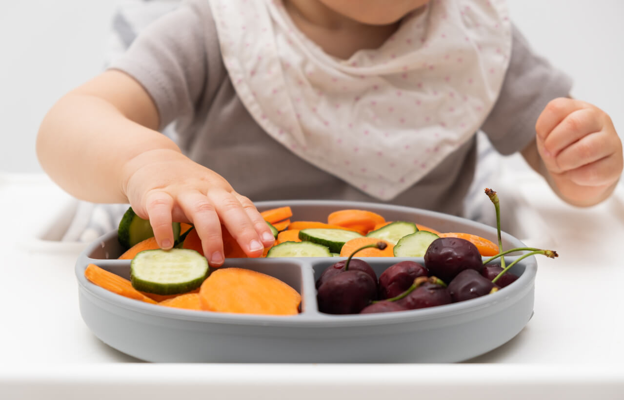 En baby som lærer å spise mat ved hjelp av BLW.