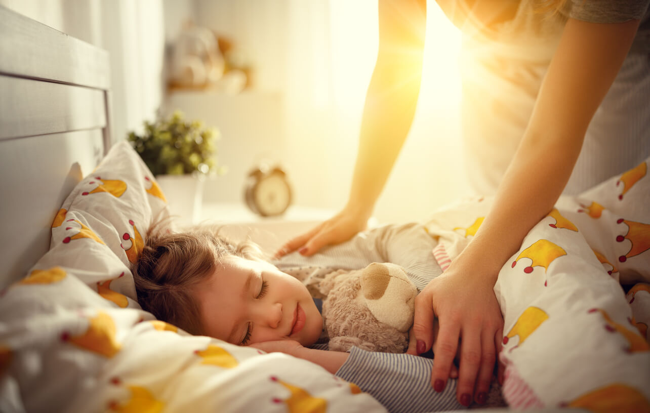 Une maman qui réveille sa fille au lit.