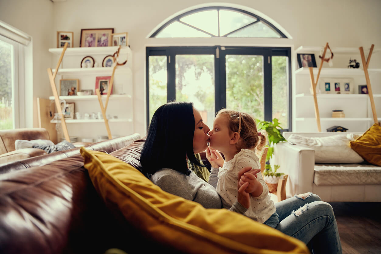 A mother kissing her toddler daughter on the mouth.