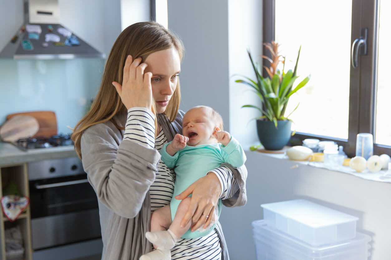 Un bébé qui pleure dans les bras de sa maman.