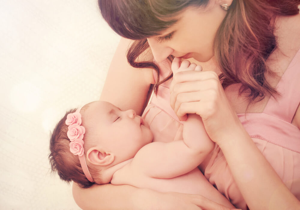 Duft eines Neugeborenen - Mutter küsst den Fuß ihres Babys