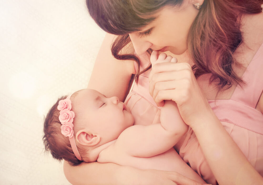 Une maman et son bébé qui dort dans ses bras.