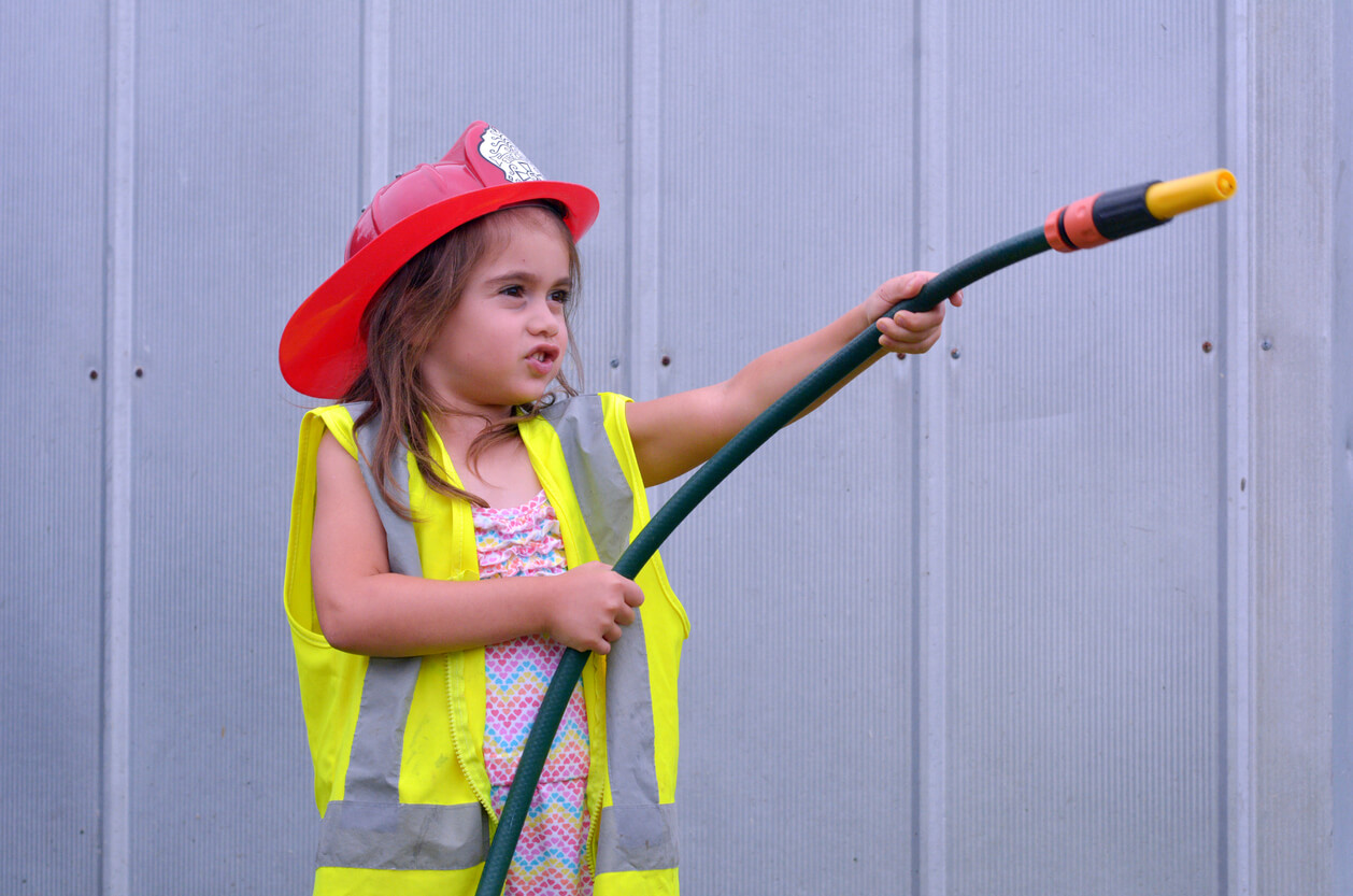A young girl pretending to be a firefighter.
