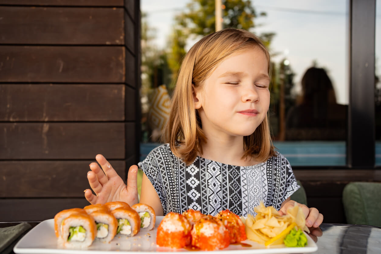 Une jeune fille devant une assiette de sushis.