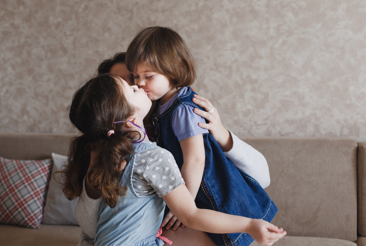 Two sisters kissing each other on the mouth.