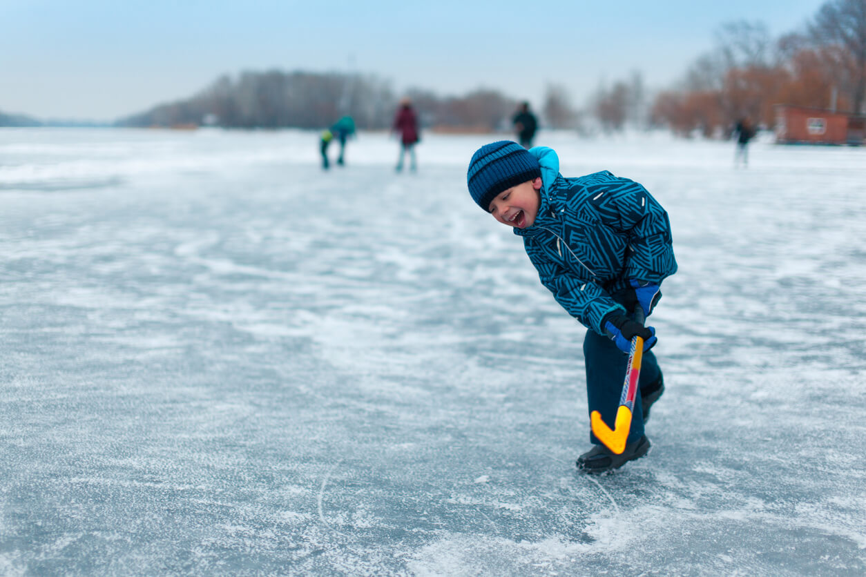 A child playing hockey on a frozen lake