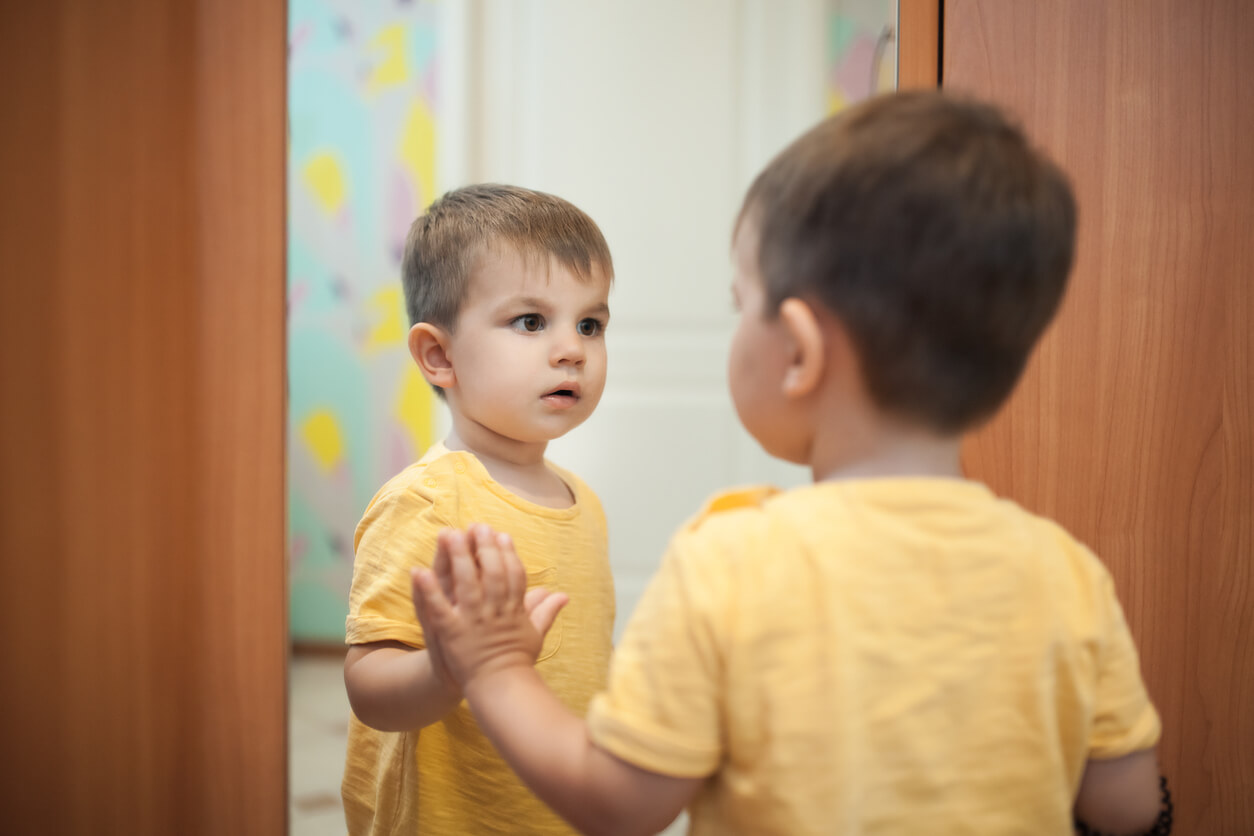 A toddler playing in front of a mirror.