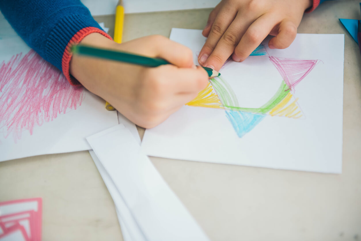 Ett barn som ritar en stjärna i olika färgpennor.