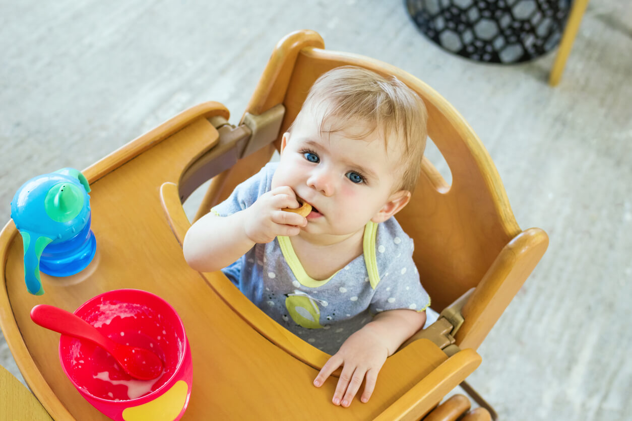 Un bébé qui mange sur une chaise haute.
