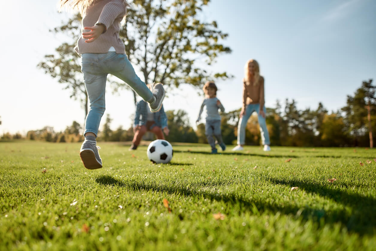 Lapset pelaavat jalkapalloa puistossa.