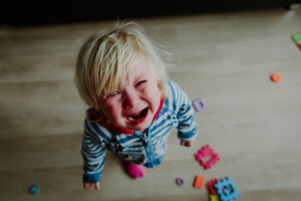 A baby looking up and crying.
