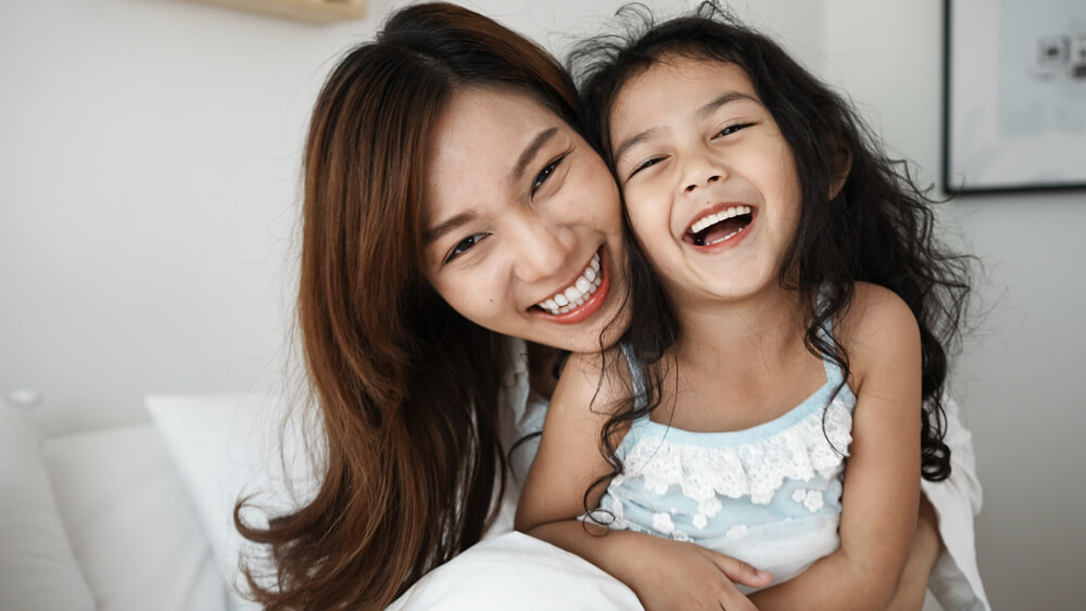 An Asian mother and daughter smiling.