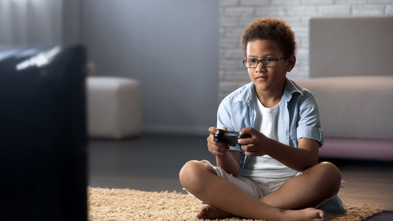 A child sitting on the floor playing a video game.