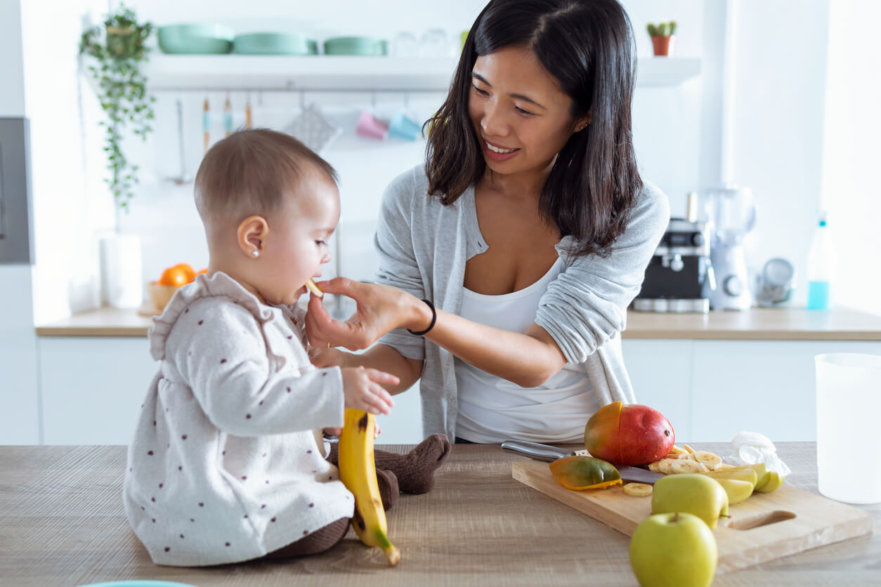 A mother offering banana to her baby.