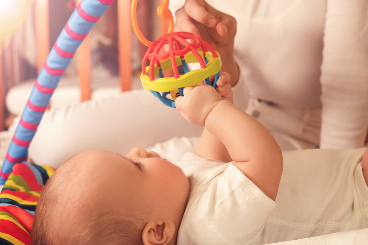 A baby playing with a baby gym.
