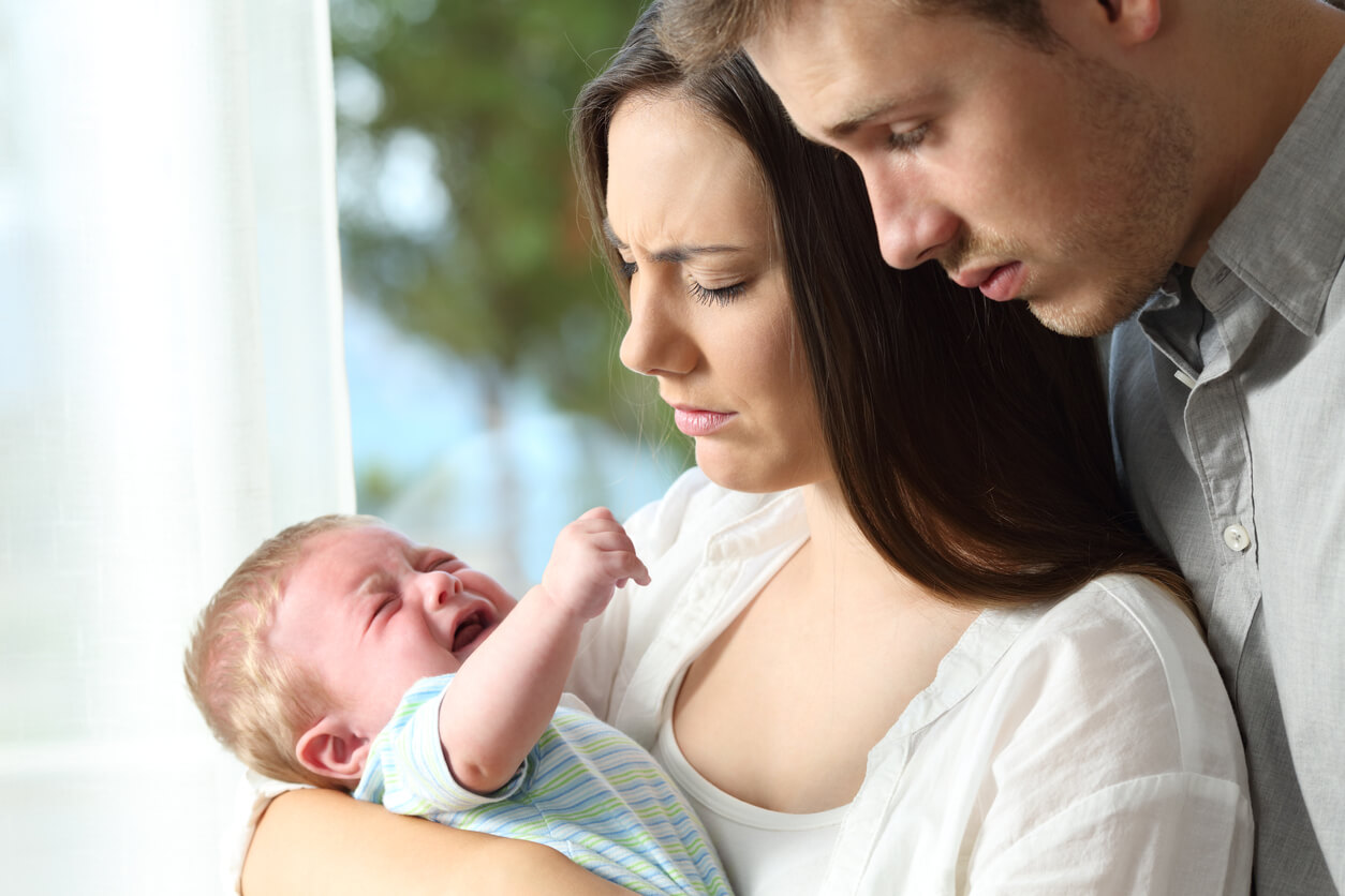 Concerned parents looking at their crying newborn.