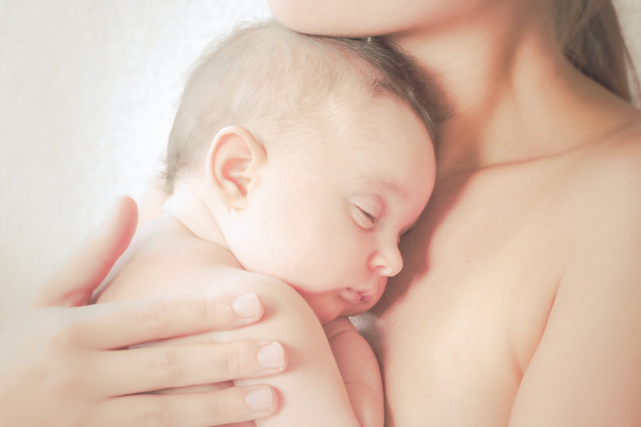 En mamma som praktiserar hud-mot-hud-kontakt med sin nyfödde.
