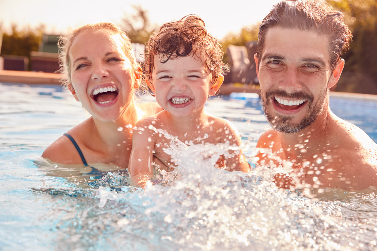 En mamma, pappa och son simmar i en pool tillsammans.
